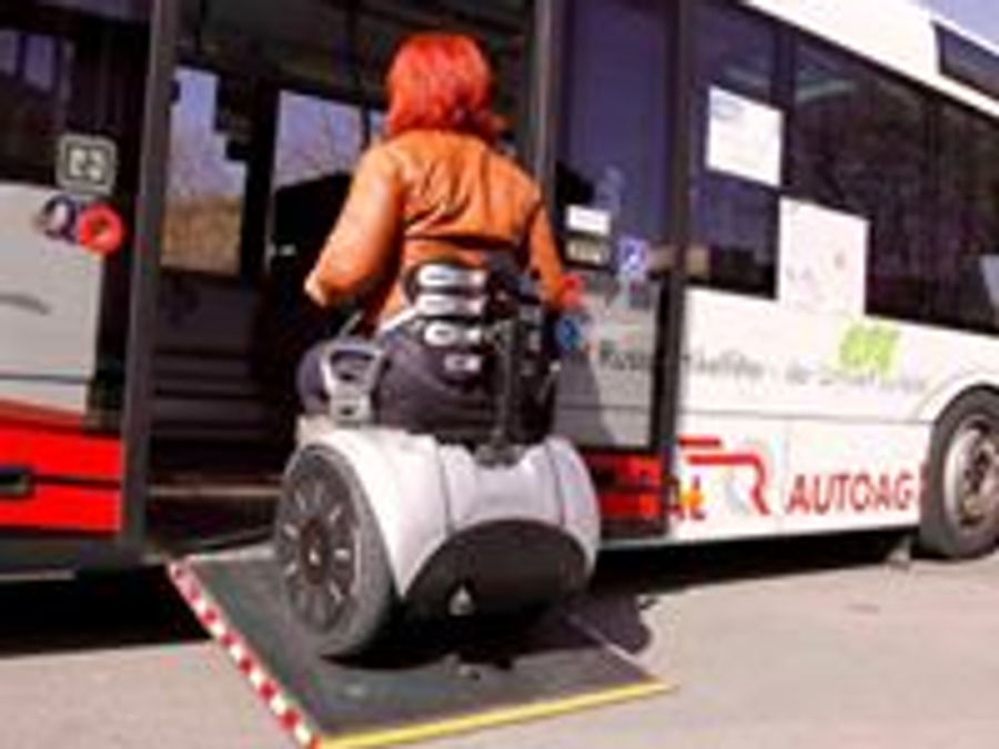 Förare på självbalanserande elrullstol på en minibuss med lyftplatta